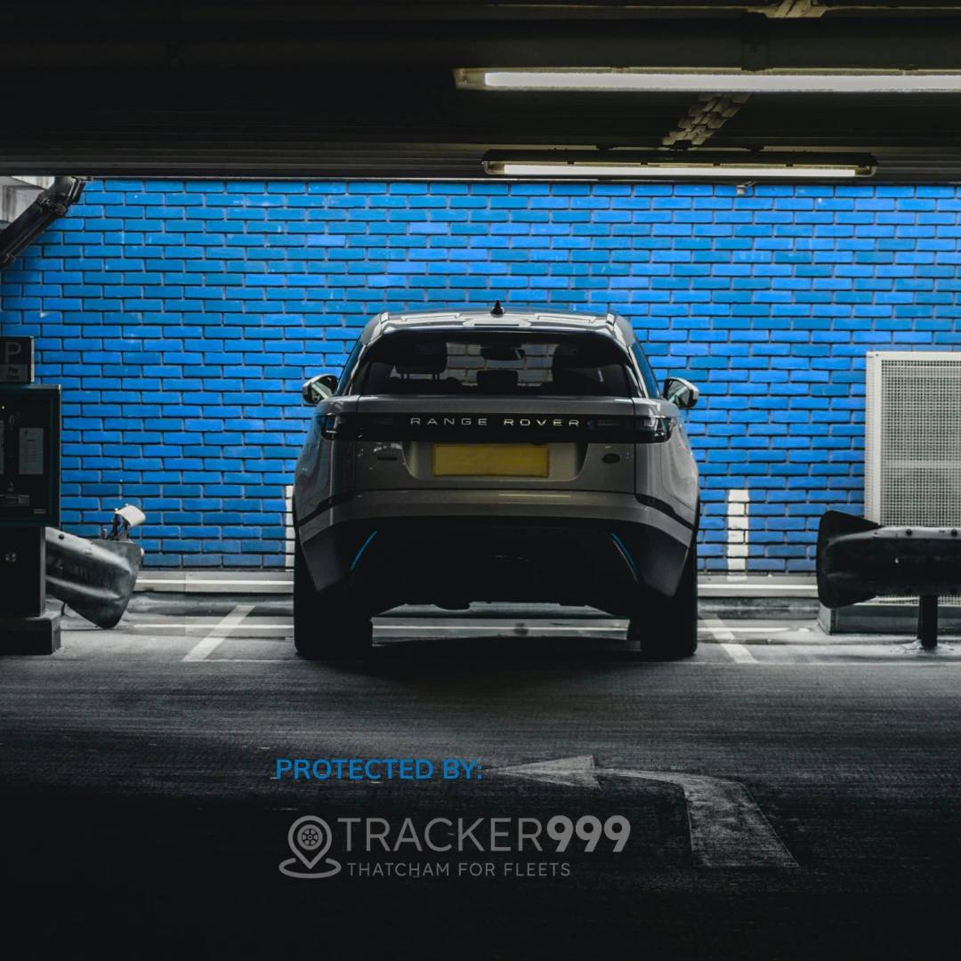 Rear view of Range Rover parked in a garage with Wholesale Telematics branding and blue wall